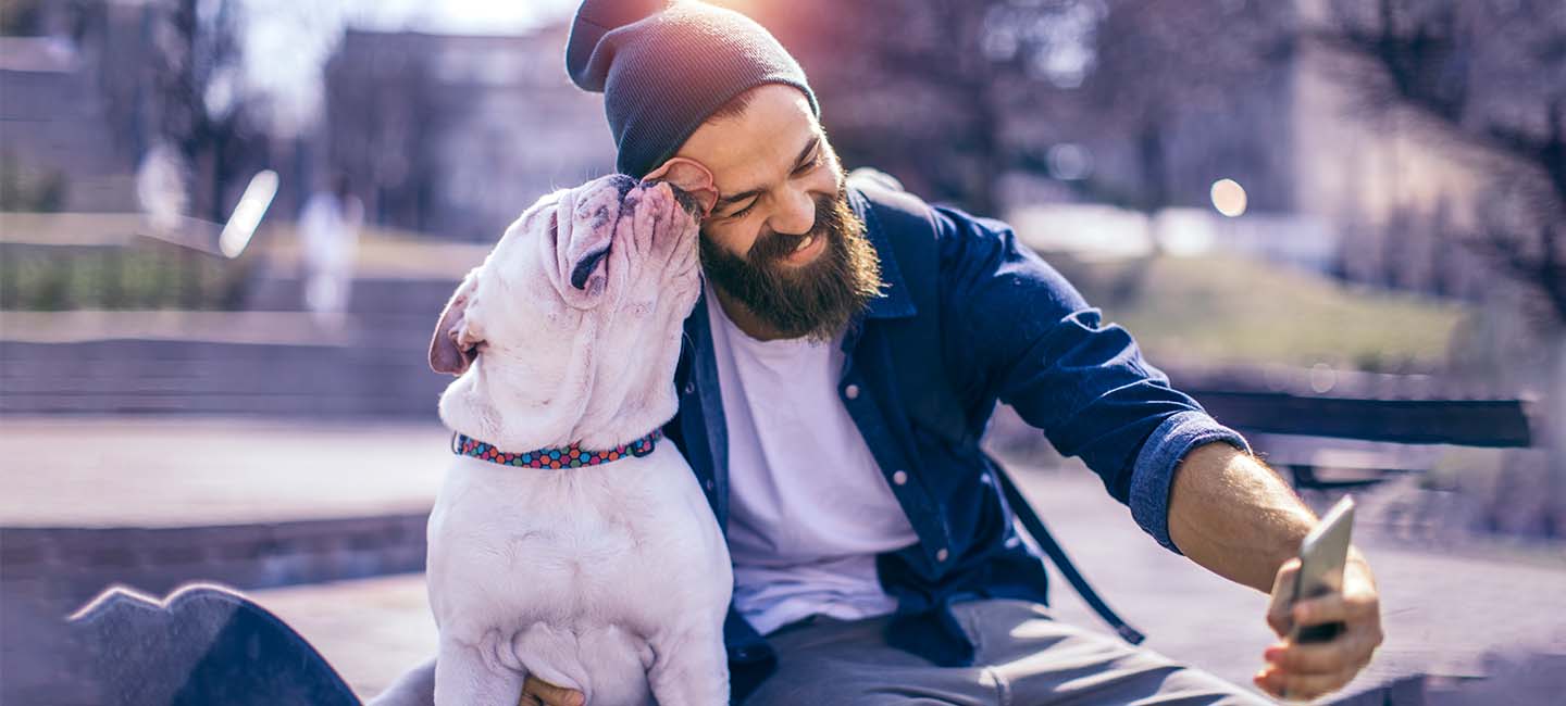 Mann sitzt mit Hund im Park