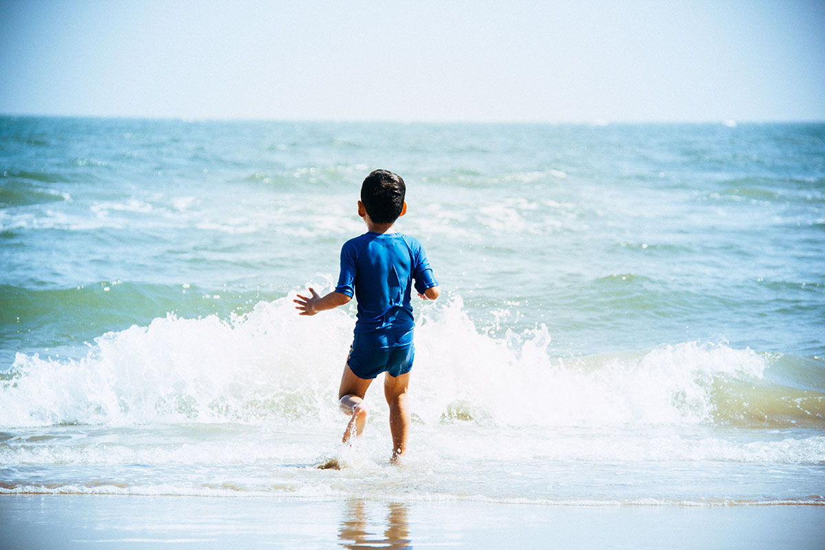 Junge spielt am Strand in den Wellen