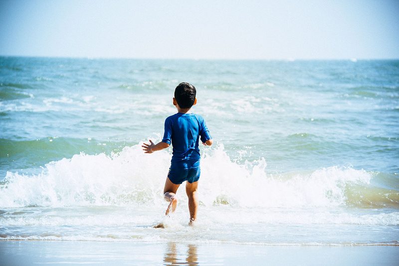 Junge spielt am Strand in den Wellen