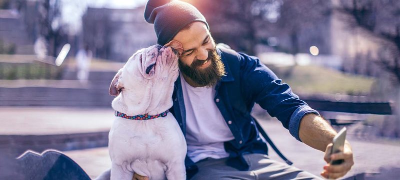 Mann sitzt mit Hund im Park