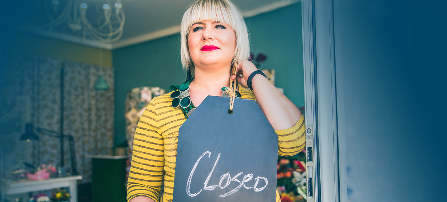 Frau mit "Geschlossen"-Schild in der Hand