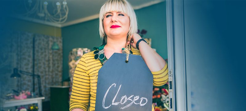 Frau mit "Geschlossen"-Schild in der Hand
