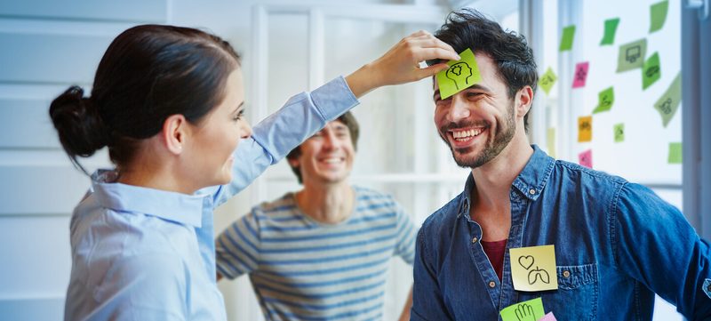 Frau klebt Post It an Kopf von Mann