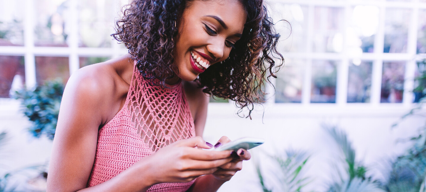 Frau bedient ihr Smartphone und lacht
